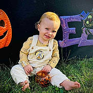 Phoniex is registered to the contest to win money with this photo: child, toddler, grass, barefoot, winnie_the_pooh, overalls, pumpkin, jack_o_lantern, halloween, decorations, smiling, outdoor, cute, jar, toy, orange, purple, spider, festive, holiday