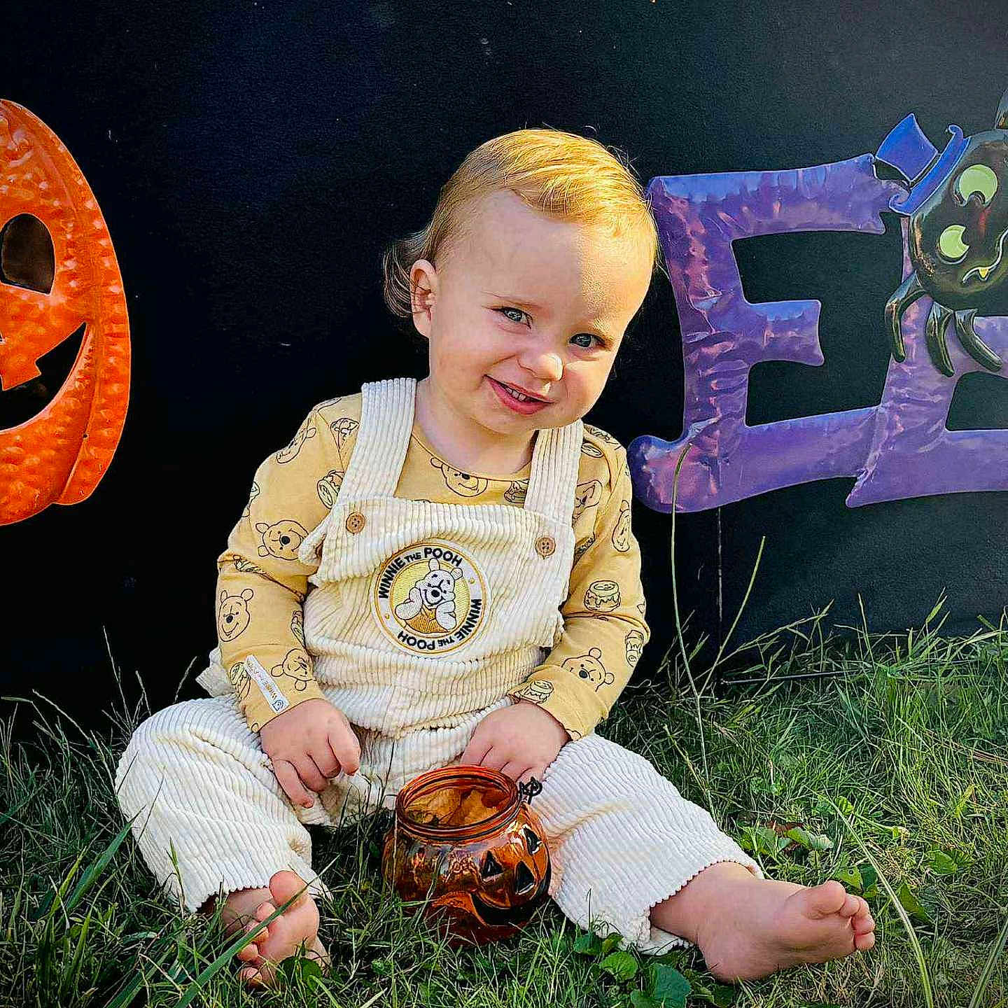 Phoniex is registered to the contest to win money with this photo: barefoot, child, cute, decorations, festive, grass, halloween, holiday, jack_o_lantern, jar, orange, outdoor, overalls, pumpkin, purple, smiling, spider, toddler, toy, winnie_the_pooh
