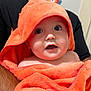 Emilio joined the competition — help win amazing prizes! baby, child, towel, orange, hood, face, eyes, skin, person, portrait, expression, indoor, adult_arm, holding, cute, infant, cloth, closeup, curious, black_shirt