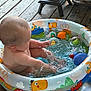 baby, child, inflatable_pool, water, splashing, toy, colorful, deck, wooden_floor, hand, footwear, summer, play, indoors, fun, person, skin, head, arm, leg
