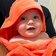 Emilio joined the competition — help win amazing prizes! baby, infant, towel, orange, hood, cute, face, eyes, expression, skin, person, child, wrapped, cloth, indoor, adult, holding, portrait, closeup, smile