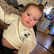 Hazel Hamby joined the competition — help win amazing prizes! toddler, child, indoor, white_sweatshirt, minnie_mouse, blue_eyes, rosy_cheeks, curly_hair, blanket, paw_print, kitchen, floor, wooden_floor, cabinet, person, clothing, baby, furniture, home, casual
