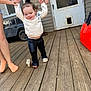 Hazel Hamby joined the competition — help win amazing prizes! toddler, child, adult, hands, tattoo, porch, wood, door, window, toy, shoe, clothing, black_pants, white_sweater, footwear, orange_socks, snow_shovel, vehicle, outdoor, play