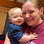 baby, woman, smiling, indoor, ceiling_fan, wooden_ceiling, hug, happy, child, person, clothing, tshirt, diaper, face, closeup, portrait, family, interaction, candid, casual