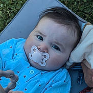 Emy participe au concours pour gagner de l'argent avec cette photo : baby, blanket, blue_clothing, child, closeup, cushion, cute, expression, face, grass, hand, head, infant, outdoor, pacifier, person, portrait, skin, toy, young