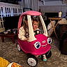 child, toy_car, pink, indoor, living_room, car, playtime, smile, fun, kid, furniture, carpet, curtains, table, television, cushion, socks, happy, person, play