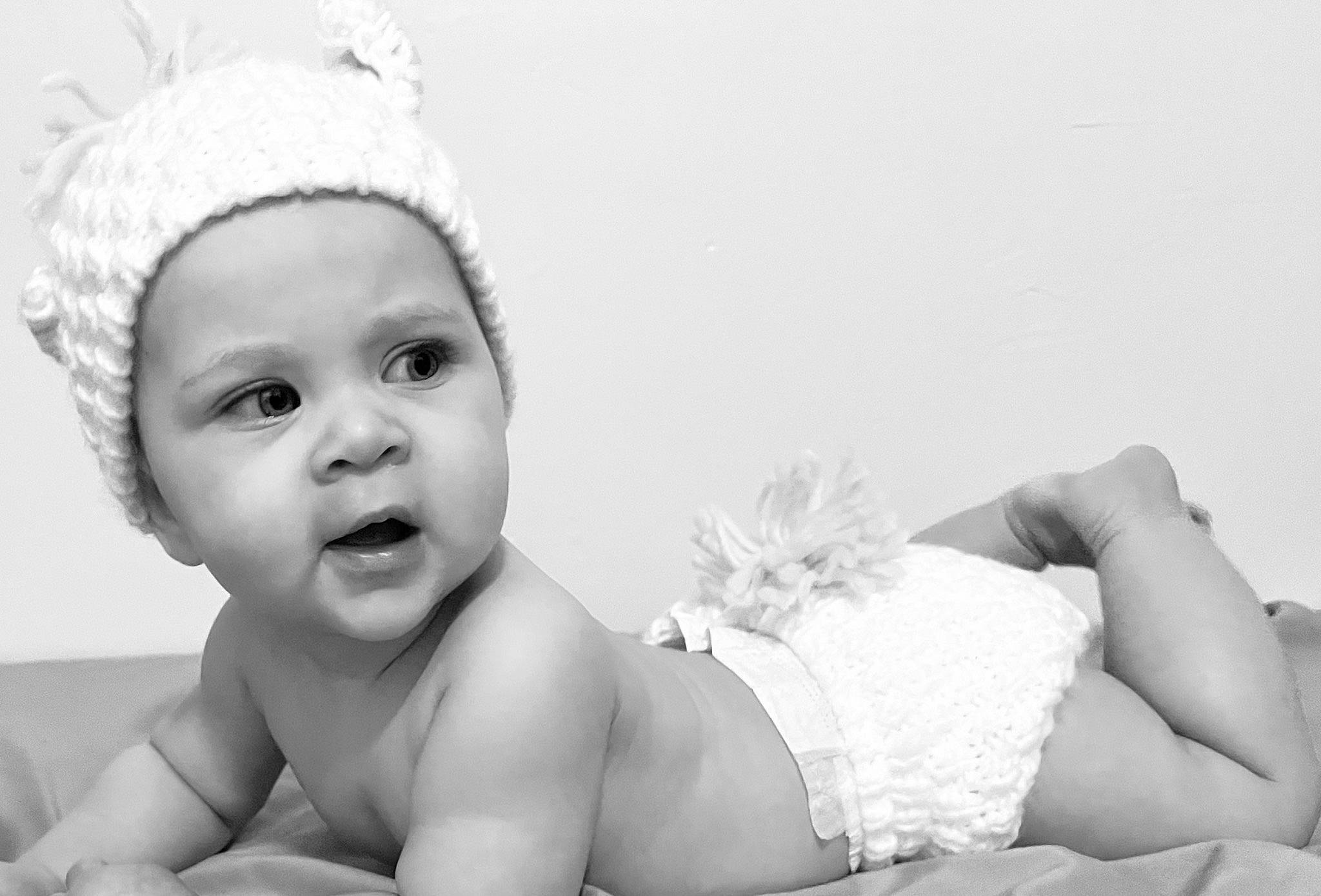 Scarlett is registered to the contest to win money with this photo: baby, black, cap, comfort, ear, eye, finger, flash_photography, gesture, happy, head, headgear, headwear, human_body, knee, monochrome, monochrome_photography, person, photograph, skin