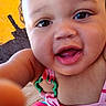 baby, black_wall, child, close_up, clothing, colorful, curly_hair, face, finger, happy, outdoor, person, pink_clothes, playful, portrait, skin, smile, toddler, yellow_wall, young_child