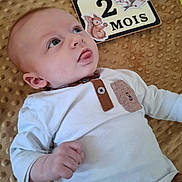 éliot a rejoint le concours — aidez-le/la à gagner de superbes lots ! baby, infant, child, white_shirt, brown_blanket, age_card, 2_months, cute, tongue_out, lying_down, portrait, close_up, hand, face, blue_eyes, clothing, illustration, animal_sticker, soft_texture, newborn
