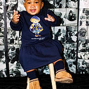 Jada is registered to the contest to win money with this photo: baby, child, infant, sitting, stool, portrait, smiling, happy, indoors, fashion, clothing, dress, boots, teddy_bear, sweater, photography, photo_collage, wall, black_and_white, studio