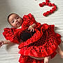 baby, celebration, child, clothing, colorful, cute, dress, fabric, flamenco_style, happy, infant, lying_down, number_three, person, polka_dot, portrait, red_dress, roses, tongue_out, white_background