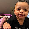Aliya is registered to the contest to win money with this photo: baby, child, infant, smiling, portrait, close_up, face, teeth, eyes, black_shirt, pink_blanket, cozy, indoor, bed, seated, happy, playful, home, photography, adorable