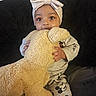 Aliya is registered to the contest to win money with this photo: baby, child, toddler, portrait, face, wide_eyed, cuddling, teddy_bear, stuffed_animal, toy, bow_headband, pajamas, mickey_mouse, smiling, sitting, indoors, couch, blanket, cozy, close_up