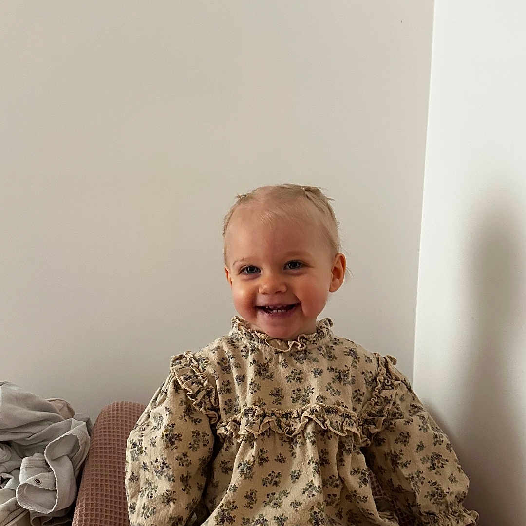 Lysia a rejoint le concours — aidez-le/la à gagner de superbes lots ! toddler, child, smile, sitting, floral_clothing, white_tights, frilly_socks, changing_pad, indoor, wall, happy, cute, infant, person, baby, young_child, fashion, portrait, seated, clothing