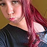 young_person, red_hair, curly_hair, pouty_face, black_shirt, graphic_tshirt, portrait, indoor, casual, long_hair, female, playful_expression, selfie, closeup, person, head_and_shoulders, plain_background, fashion, teenager, natural_light