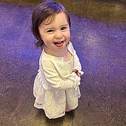 Athena joined the competition — help win amazing prizes! cardigan, child, cute, expression, face, floor, hair, happy, indoors, looking_up, person, playful, portrait, purple_light, small_person, smiling, standing, toddler, white_dress, young_child