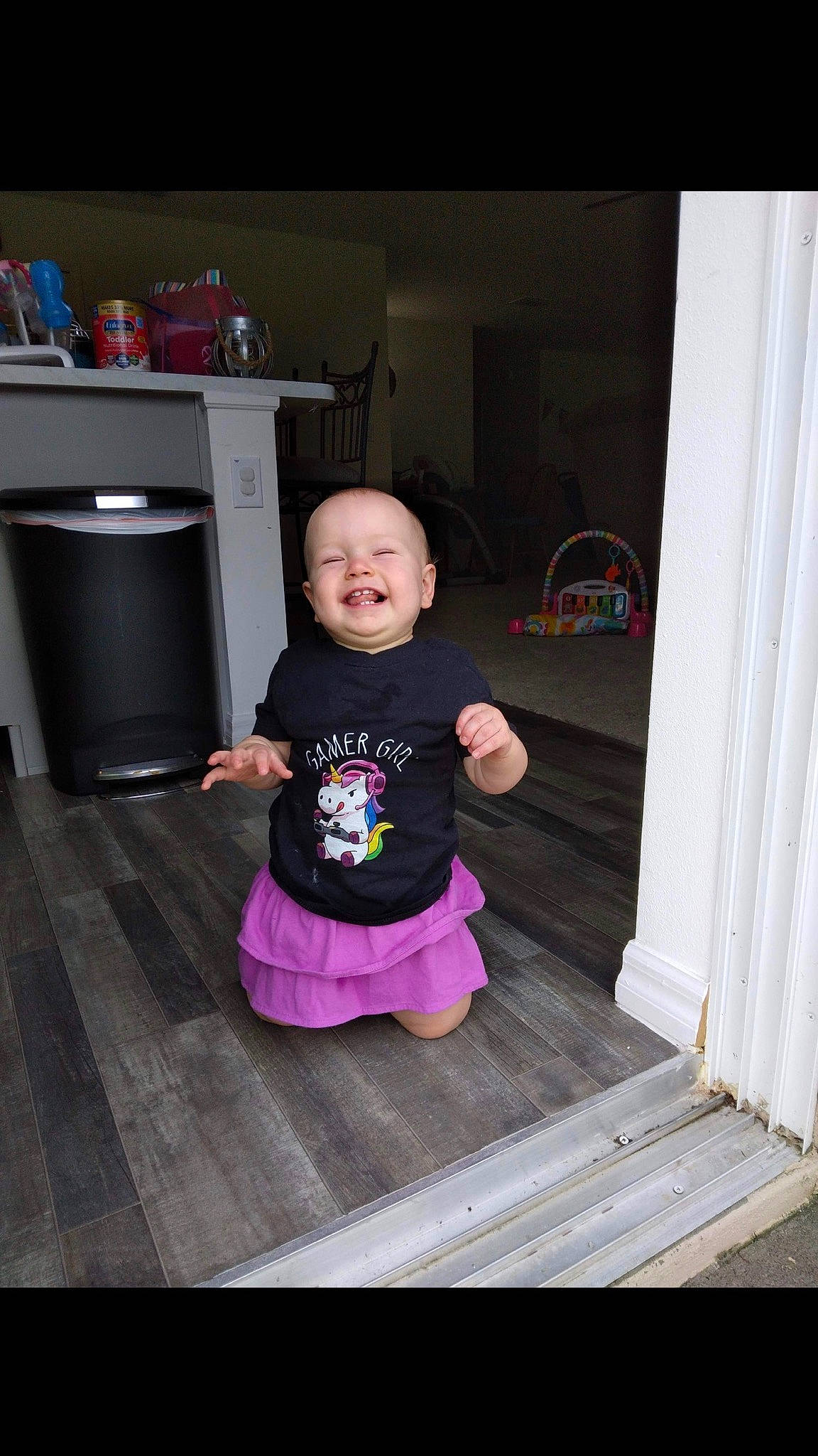 Laurel joined the competition — help win amazing prizes! baby_toddler_clothing, cabinetry, door, drawer, face, floor, flooring, gas_stove, hardwood, home_appliance, joy, kitchen, kitchen_appliance, person, product, purple, sleeve, smile, standing, t_shirt