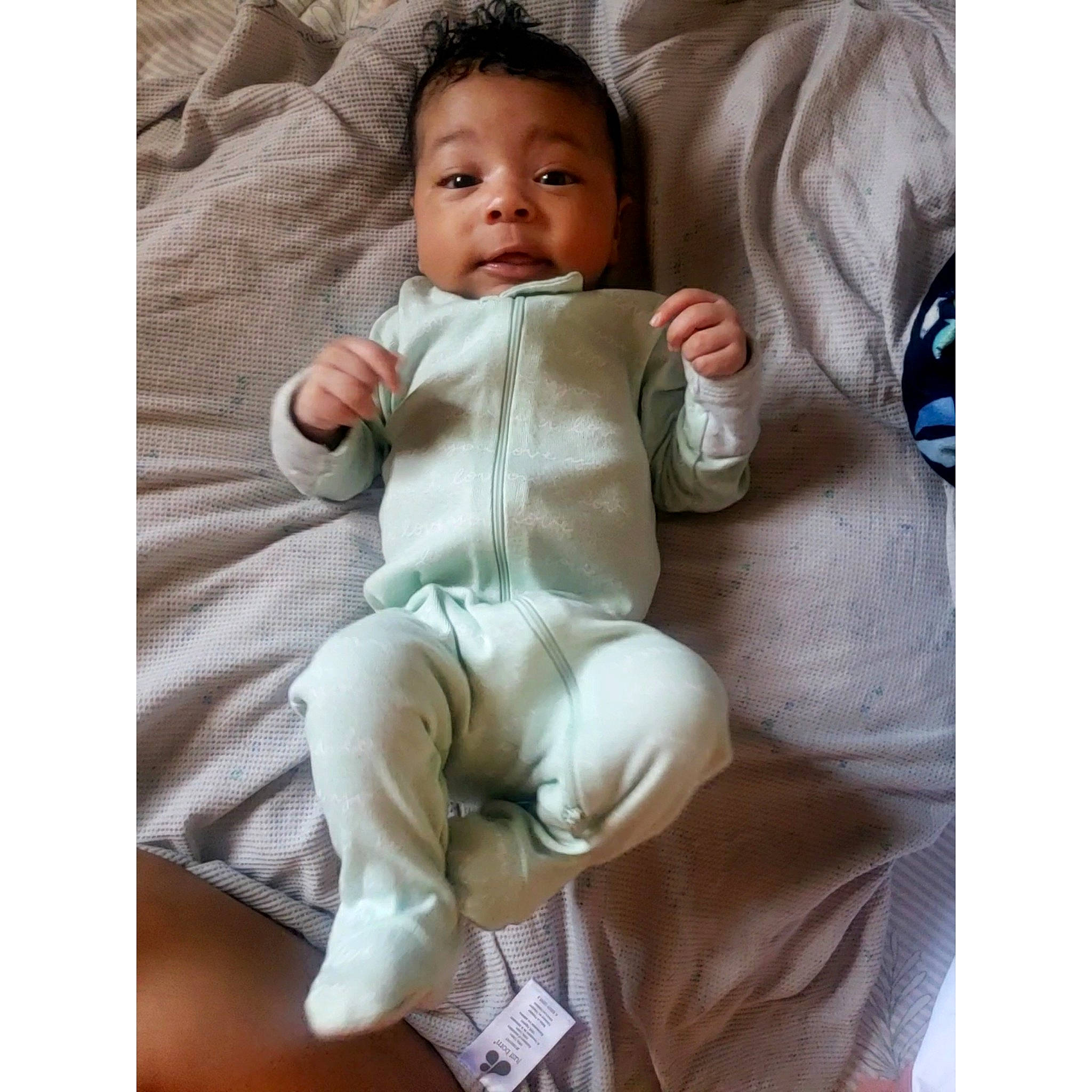 Malachi is registered to the contest to win money with this photo: arm, baby, baby_products, baby_sleeping, baby_toddler_clothing, child, comfort, face, foot, gesture, happy, head, linens, neck, person, sitting, sleeve, smile, textile, thumb