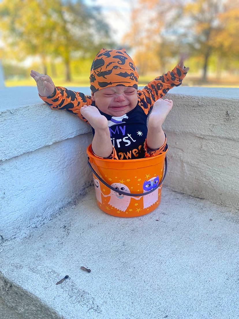 Landyn is registered to the contest to win money with this photo: asphalt, baby, electric_blue, eyewear, fun, happy, hat, headwear, leisure, orange, person, personal_protective_equipment, recreation, sand, sitting, soil, sunglasses, toddler, tree, water