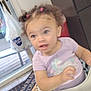 toddler, child, high_chair, purple_shirt, unicorn, curly_hair, pink_hair_ties, kitchen, microwave, plastic_bag, door, floor_tile, mat, window, cabinet, table, indoor, person, baby, home