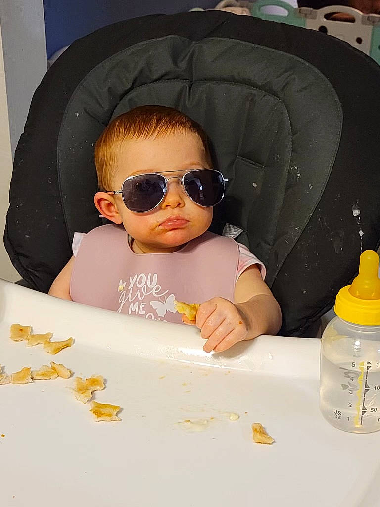 Scarlet Rose is registered to the contest to win money with this photo: baby, baby_toddler_clothing, bottle, cheek, comfort, dishware, drinkware, eyewear, facial_expression, flooring, fun, goggles, hairstyle, person, plastic_bottle, product, sleeve, sunglasses, toddler, vision_care