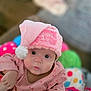 baby, infant, pink_hat, christmas_hat, holiday, candy_cane_pattern, cute, face, eyes, clothing, indoors, toy, colorful, child, portrait, festive, soft_texture, young_child, looking_at_camera, warm_lighting