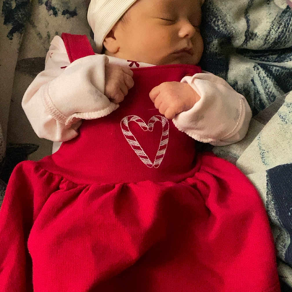 Misty joined the competition — help win amazing prizes! baby, blanket, bow, child, clothing, cozy, cute, feet, hands, headband, heart_design, indoors, infant, newborn, peaceful, portrait, red_dress, resting, sleeping, soft_lighting