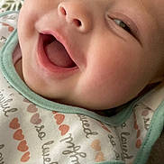 Zhavia is registered to the contest to win money with this photo: baby, close_up, smiling, happy, infant, face, bib, clothing, cute, portrait, child, expression, joy, skin, mouth_open, eyes, indoor, soft_light, blanket, pattern