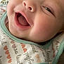 baby, close_up, smiling, happy, infant, face, bib, clothing, cute, portrait, child, expression, joy, skin, mouth_open, eyes, indoor, soft_light, blanket, pattern
