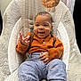 baby, infant, smiling, happy, sitting, baby_chair, plush_toy, orange_sweater, gray_pants, brown_shoes, indoor, child, cute, cozy, clothing, person, furniture, patterned, soft_texture, playful