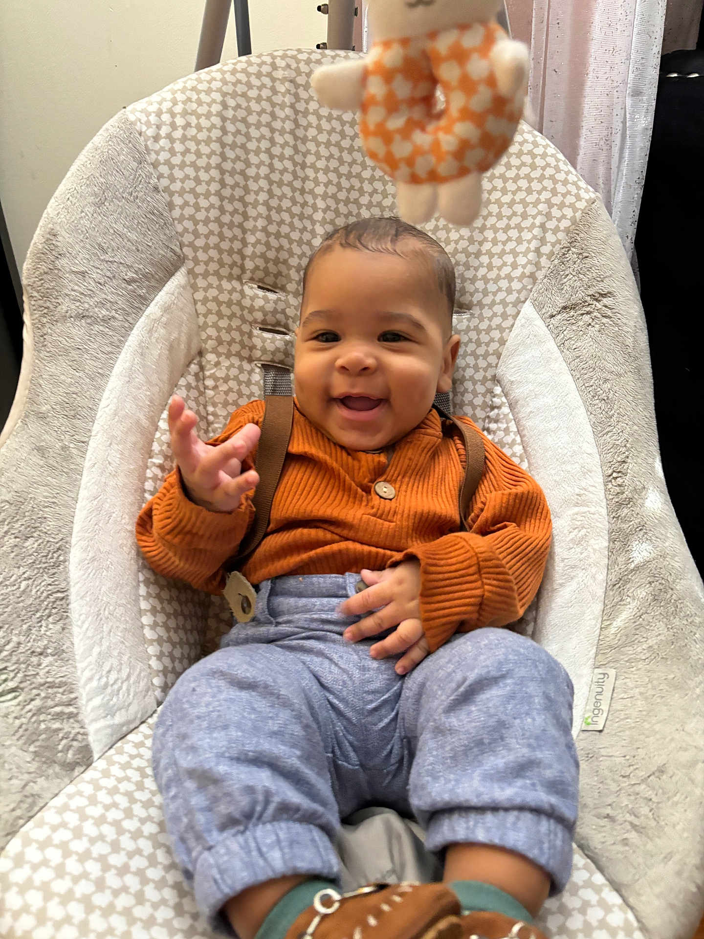 Isaiah is registered to the contest to win money with this photo: baby, infant, smiling, happy, sitting, baby_chair, plush_toy, orange_sweater, gray_pants, brown_shoes, indoor, child, cute, cozy, clothing, person, furniture, patterned, soft_texture, playful