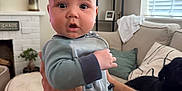Henry joined the competition — help win amazing prizes! adult, baby, black_dog, blanket, carpet, couch, curtains, dog, fireplace, hands, home_interior, infant, living_room, mirror, pajamas, person, pillow, plant, shelf, window