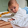 baby, infant, tummy_time, blanket, toy, crib, white_sweater, blue_jeans, floor, indoor, child, cute, portrait, looking_at_camera, hand, head, skin, expression, room, soft_lighting