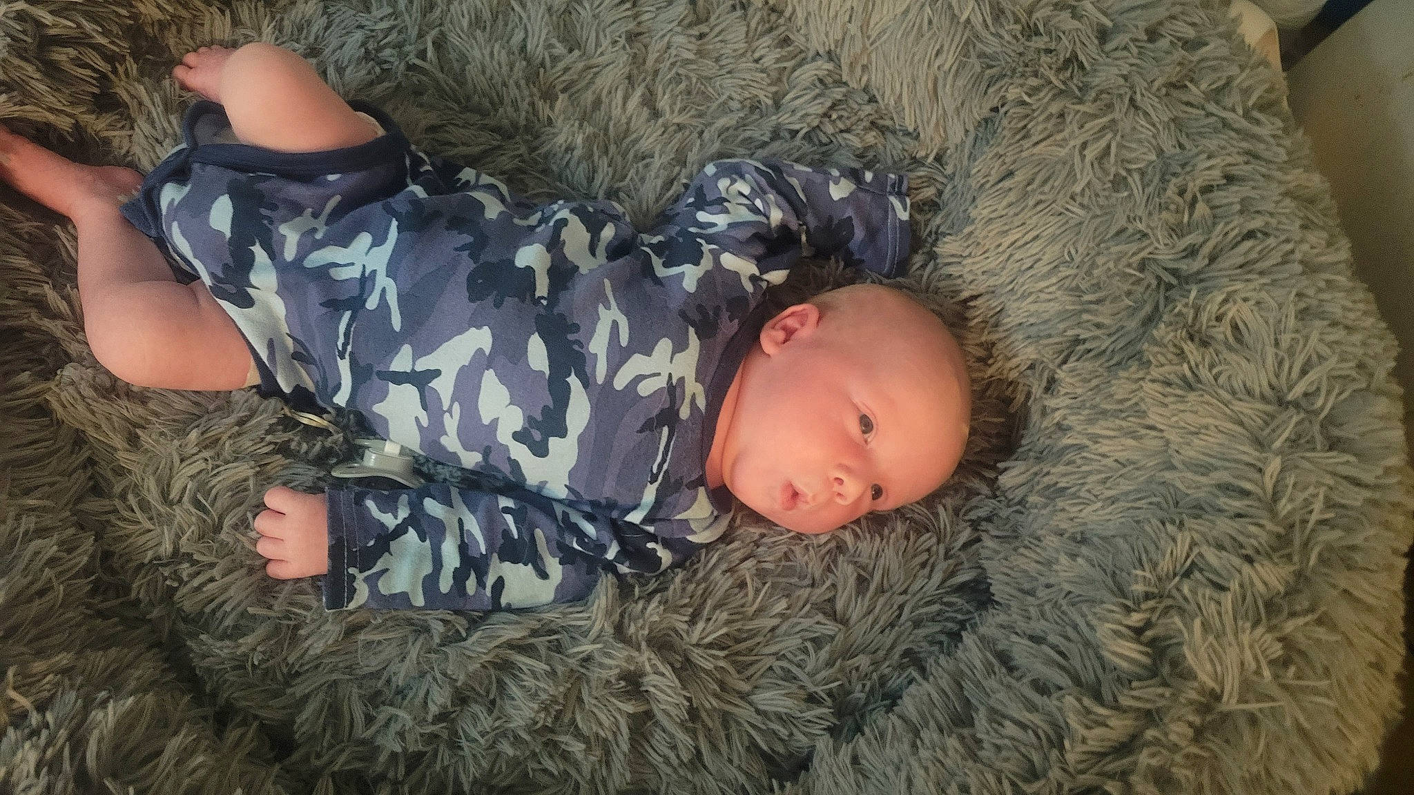 Dax is registered to the contest to win money with this photo: baby, baby_toddler_clothing, camouflage, child, comfort, fun, fur, grass, linens, military_camouflage, pattern, person, sitting, sleeve, toddler, tree, wood