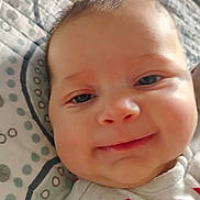 Madilynn is registered to the contest to win money with this photo: baby, smile, face, infant, close_up, quilt, pattern, bed, sleepwear, child, skin, cheeks, eyes, head, portrait, cute, young, happy, indoor, soft_lighting