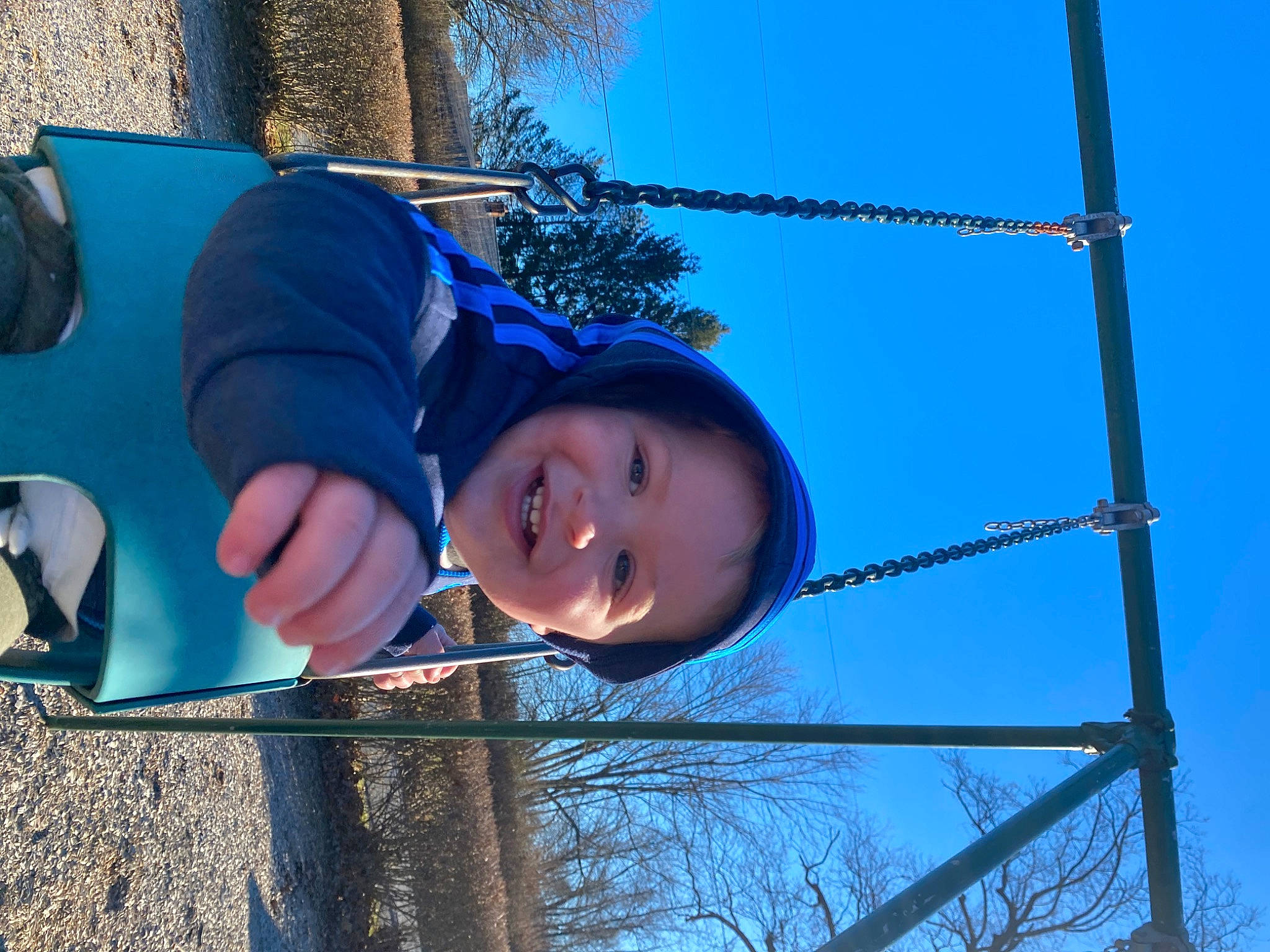 Maverick is registered to the contest to win money with this photo: baseball_cap, electric_blue, electricity, fashion_accessory, fun, happy, hat, joy, leisure, outdoor_play_equipment, person, plant, playground, recreation, sky, smile, sun_hat, swing, toddler, tree