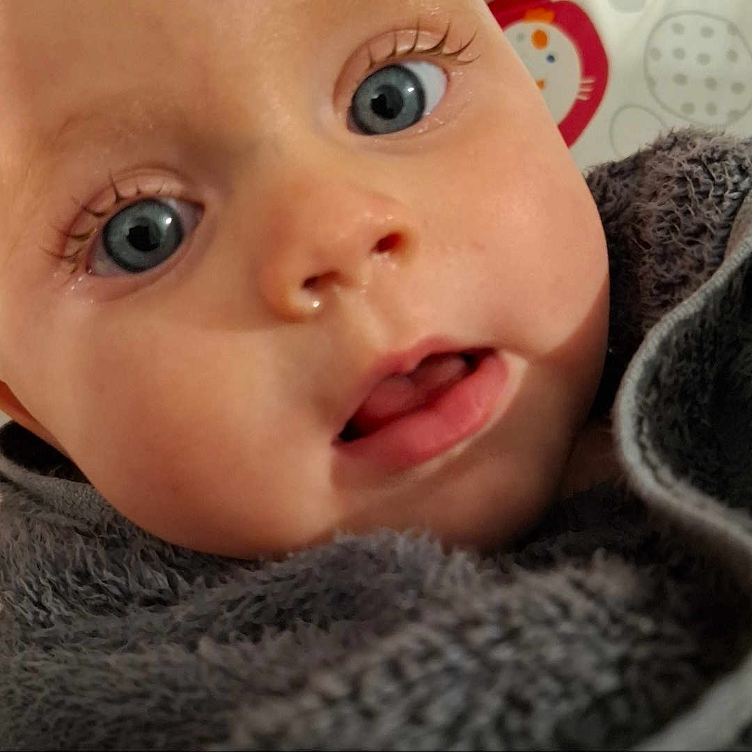 Lyla joined the competition — help win amazing prizes! baby, blanket, bodypart, bonnet, clothing, face, happy, hat, head, knitwear, mouth, newborn, person, photography, portrait, quilt, selfie, smile, sweater, towel