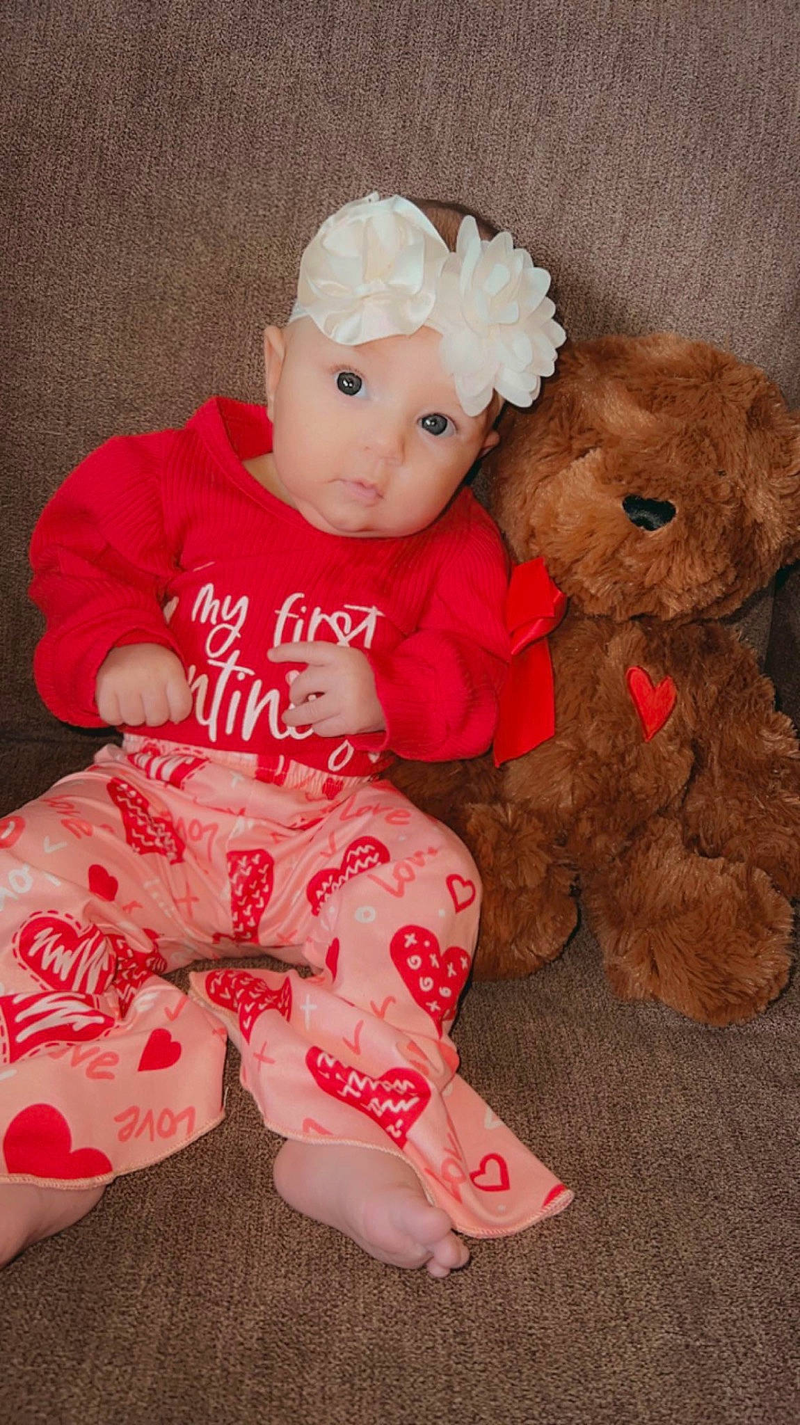 Skyla is registered to the contest to win money with this photo: baby, baby_toddler_clothing, carmine, child, comfort, fur, hat, headwear, human_leg, lap, pattern, person, pink, sitting, skin, sleeve, sock, stuffed_toy, teddy_bear, thigh