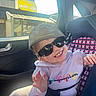 child, toddler, sunglasses, cap, car_seat, car_interior, smile, happy, clothing, hoodie, purple, seatbelt, floral_pattern, sunlight, window, person, casual, cute, portrait, baby