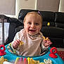 Sienna-Joan joined the competition — help win amazing prizes! baby, child, smiling, snack, chips, activity_walker, bib, hair_clip, indoor, living_room, couch, toy, play_area, happy, cute, person, seat, plastic_toy, feeding, infant
