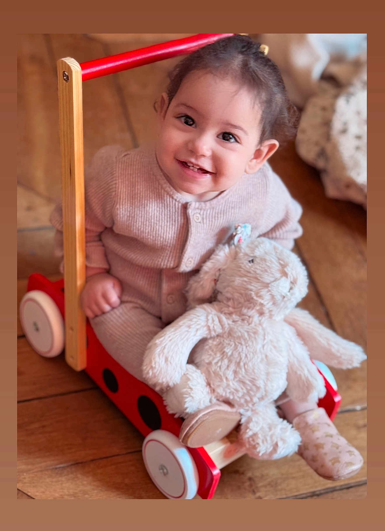 Sofia participe au concours pour gagner de l'argent avec cette photo : toddler, child, smile, toy_wagon, stuffed_animal, bunny, wooden_floor, indoor, cozy, cute, happy, clothing, sitting, playtime, infant, person, soft_toy, baby, warm_lighting, wood