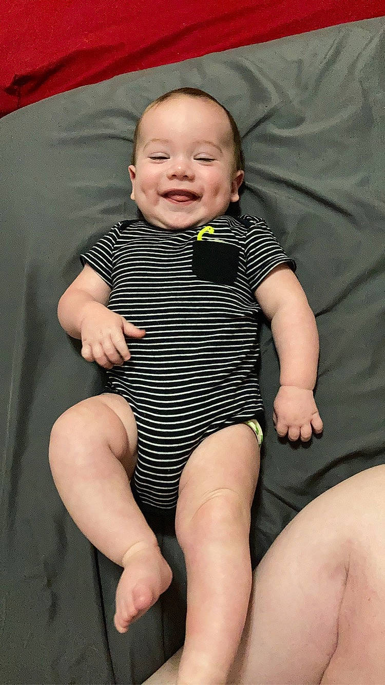 Canyon is registered to the contest to win money with this photo: arm, baby_toddler_clothing, cheek, comfort, dress, eye, face, finger, hand, happy, head, human_body, joy, leg, mouth, organ, person, skin, sleeve, smile