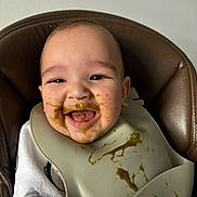 Anzo a rejoint le concours — aidez-le/la à gagner de superbes lots ! baby, high_chair, bib, food, messy, smiling, happy, face, infant, feeding, child, clothing, indoor, portrait, cute, tongue, skin, seat, mealtime, expression