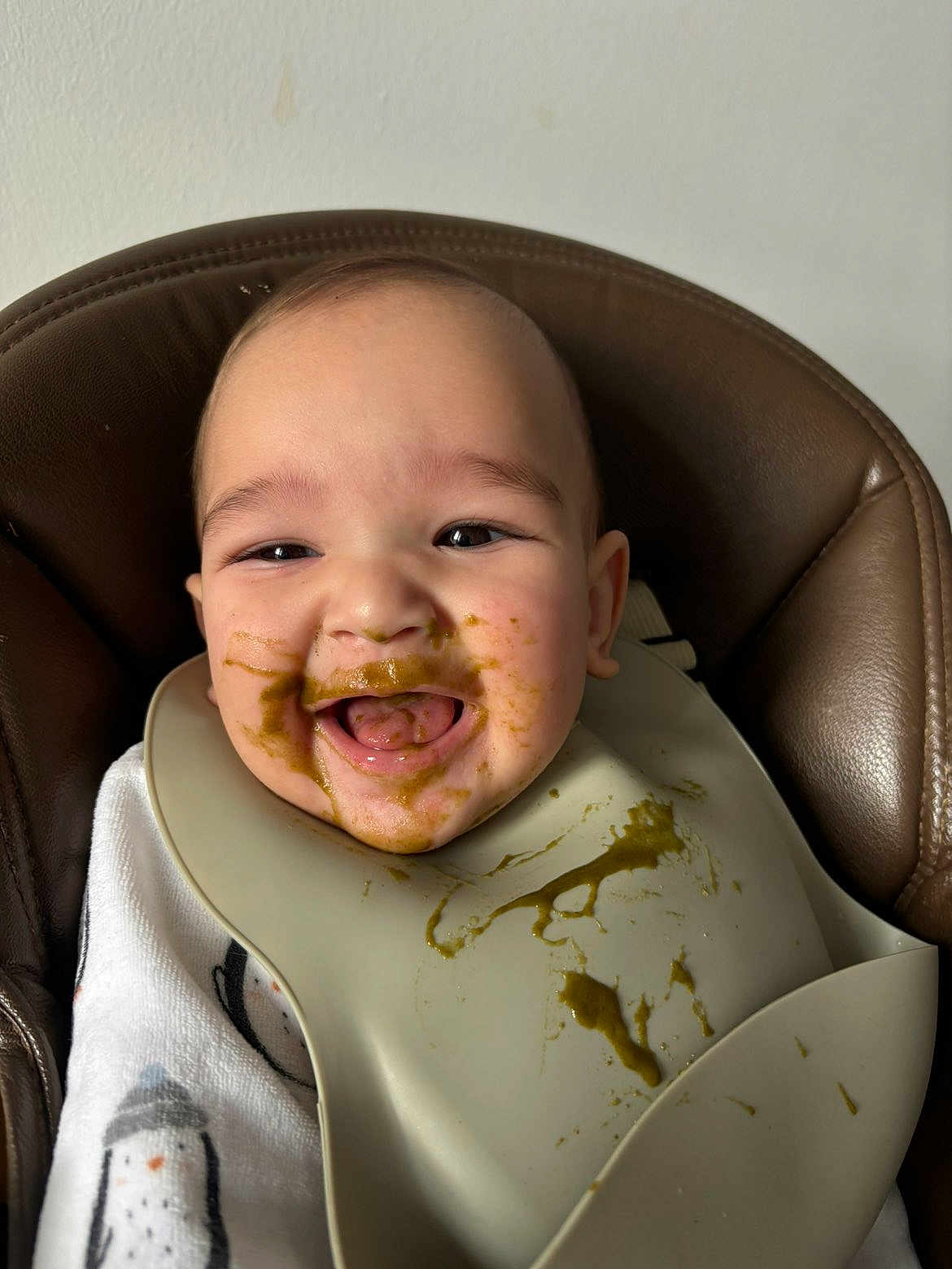 Anzo a rejoint le concours — aidez-le/la à gagner de superbes lots ! baby, high_chair, bib, food, messy, smiling, happy, face, infant, feeding, child, clothing, indoor, portrait, cute, tongue, skin, seat, mealtime, expression