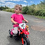 Mya participe au concours pour gagner de l'argent avec cette photo : toddler, child, tricycle, toy_bike, pink_shirt, outdoor, road, cloudy_sky, greenery, toy, teddy_bear, curly_hair, casual_clothing, summer, daylight, vehicle, playtime, happy, young_child, transportation