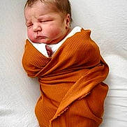 Remington is registered to the contest to win money with this photo: newborn, baby, infant, sleeping, swaddled, blanket, orange, knit, portrait, face, closed_eyes, nose, mouth, head, white_background, soft_lighting, cozy, indoors, photography, burrito