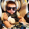 Remington is registered to the contest to win money with this photo: baby, infant, child, sunglasses, car_seat, safety_harness, blanket, floral_blanket, seated, portrait, indoors, vehicle, sleepy, serious_expression, fashion, cozy, headrest, face, baby_clothing, photography