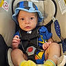 Remington is registered to the contest to win money with this photo: baby, infant, child, car_seat, seated, blue_hat, yellow_socks, blue_clothing, harness, pacifier, portrait, wide_eyed, indoors, vehicle, safety_seat, baby_clothing, feet, looking_at_camera, close_up, adorable