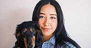 Molly is registered to the contest to win money with this photo: animal, black_and_tan, bright_lighting, closeup, companion, denim_jacket, dog, face, floppy_ears, holding, indoors, long_hair, pale_background, person, pet, portrait, puppy, selfie, smiling, woman