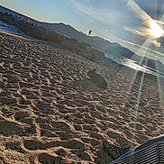 Iros participe au concours pour gagner de l'argent avec cette photo : beach, clouds, dog, footwear, landscape, lens_flare, mountains, nature, ocean, outdoor, pants, person, relaxation, rocks, sand, shoes, sky, sun, sunlight, water